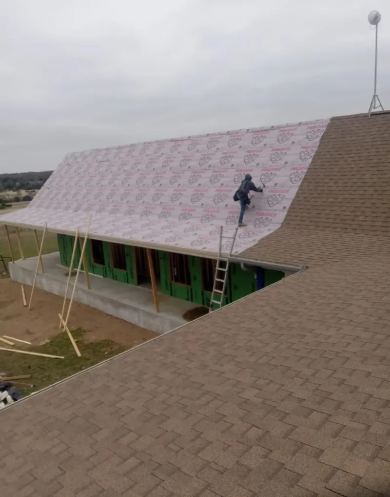 Worker preparing underlayment for a metal roof installation in Brookshire